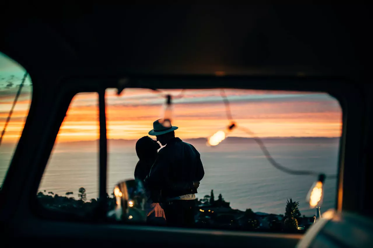 Vue à travers la fenêtre d'un van d'un couple au coucher de soleil