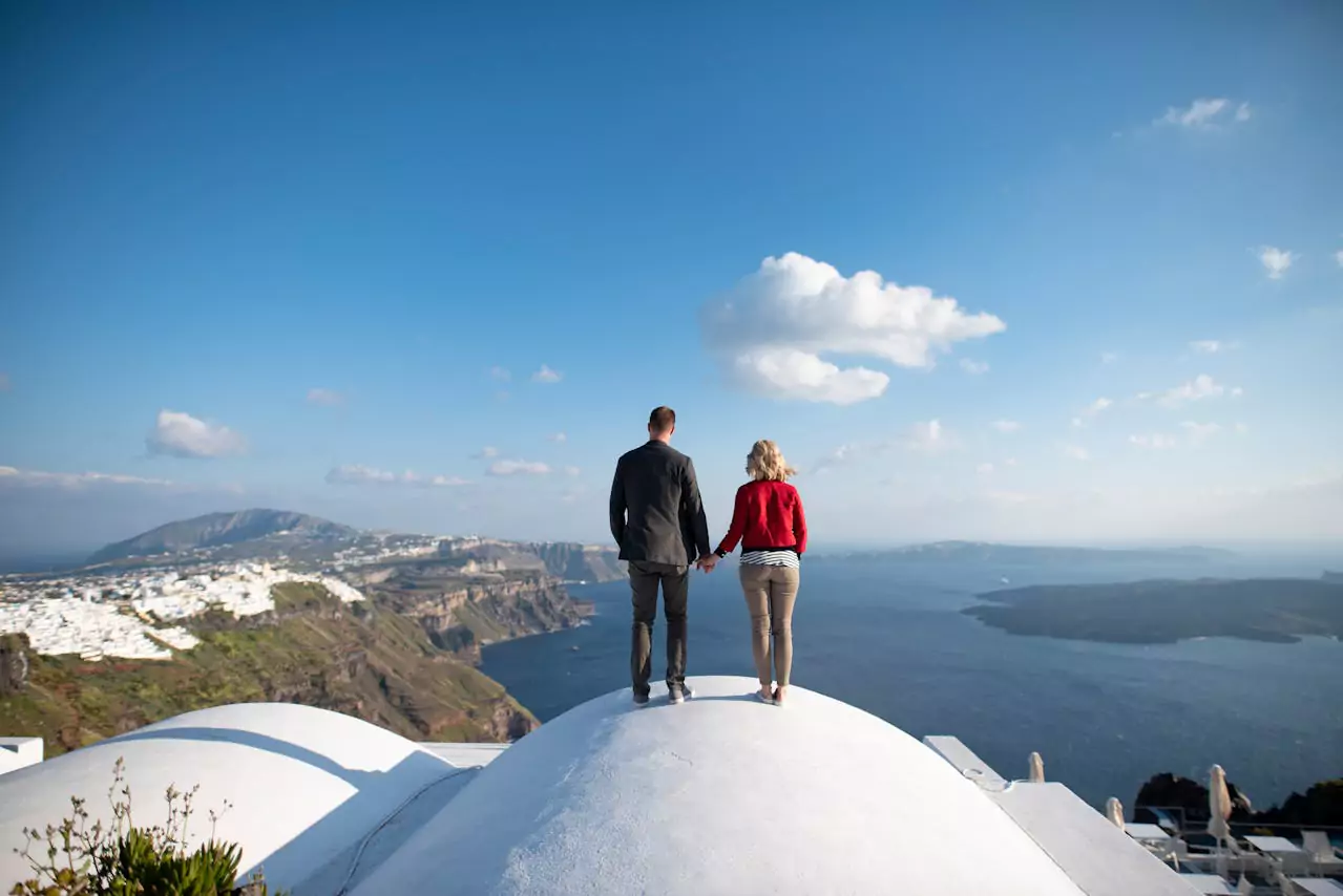 Couple se tenant la main sur le toit d'une maison à Santorin
